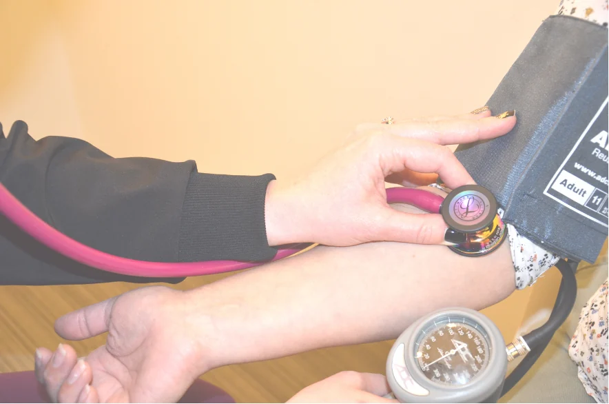A healthcare worker taking a blood pressure reading with a cuff and stethoscope