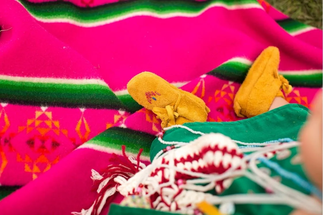 Beaded baby moccasins resting on a woven basket